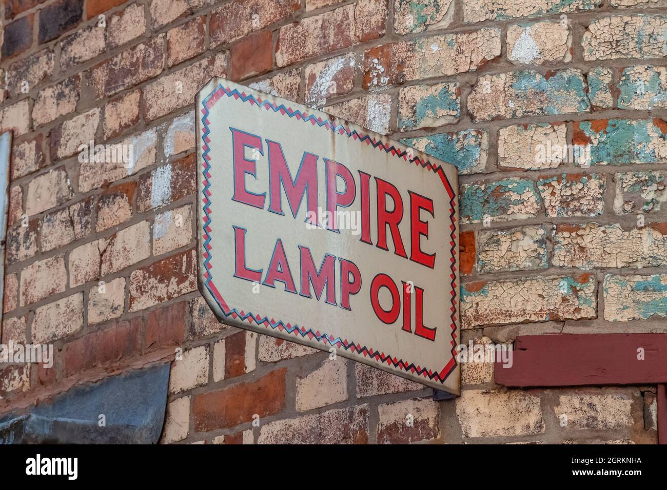 Enseigne émaillée Empire Lamp Oil sur le mur en brique décolorant Banque D'Images
