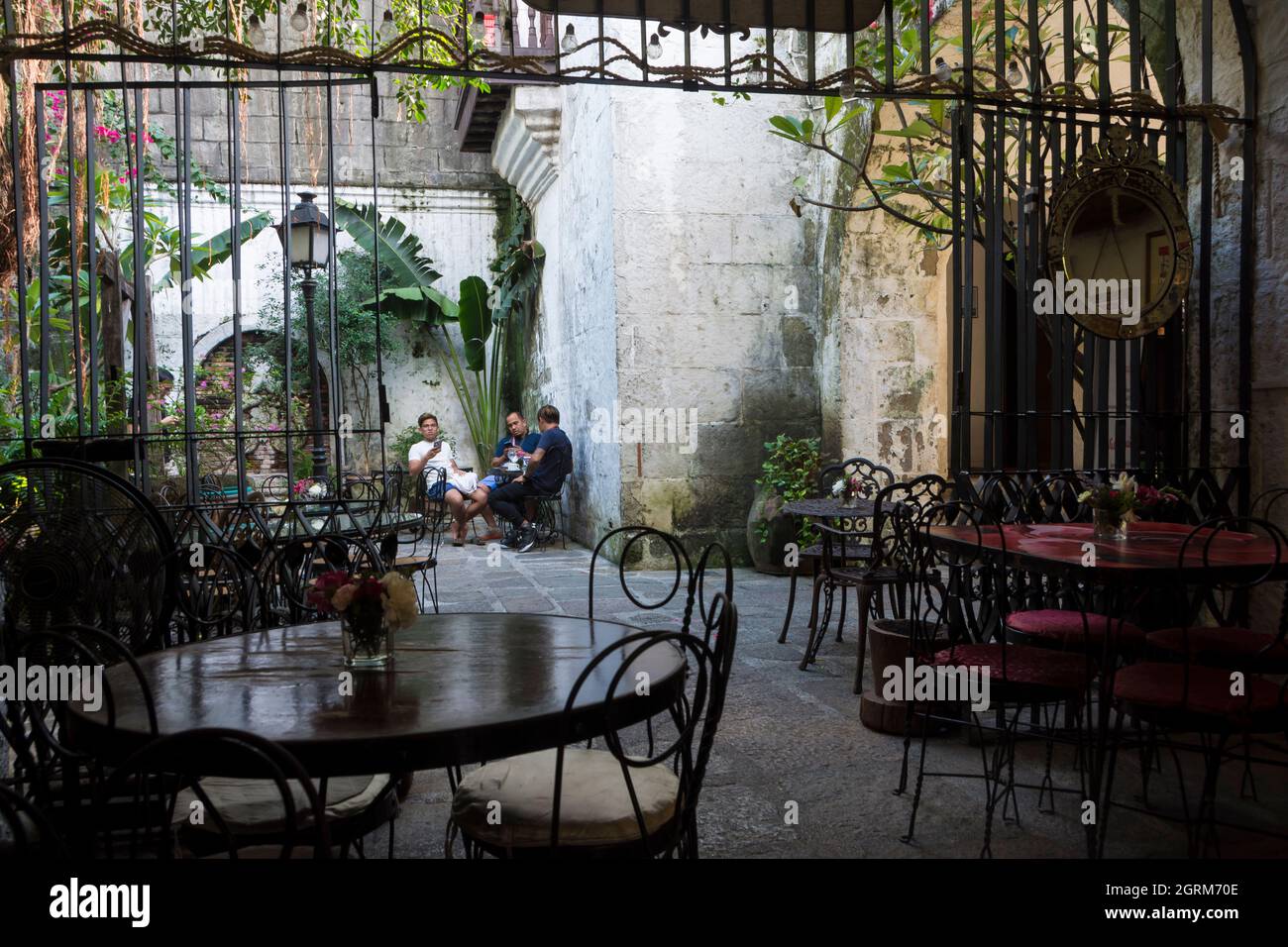 Trois hommes assis à une table dans le patio d'une maison de café à Intramuros, la zone historique fortifiée dans la ville de Manille, Philippines Banque D'Images