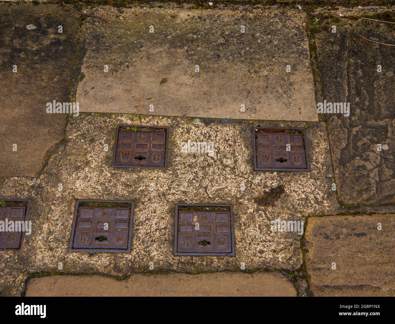 Old Cambridge Water Company couvercles de butée en métal d'eau dans le béton ancien Banque D'Images