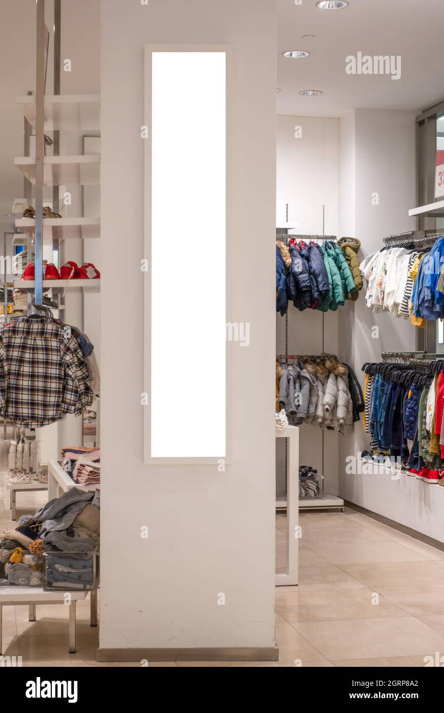 Maquette. Panneau d'affichage vertical vierge, cadre d'affiche, publicité sur le mur à l'intérieur dans le magasin de vêtements pour enfants Banque D'Images