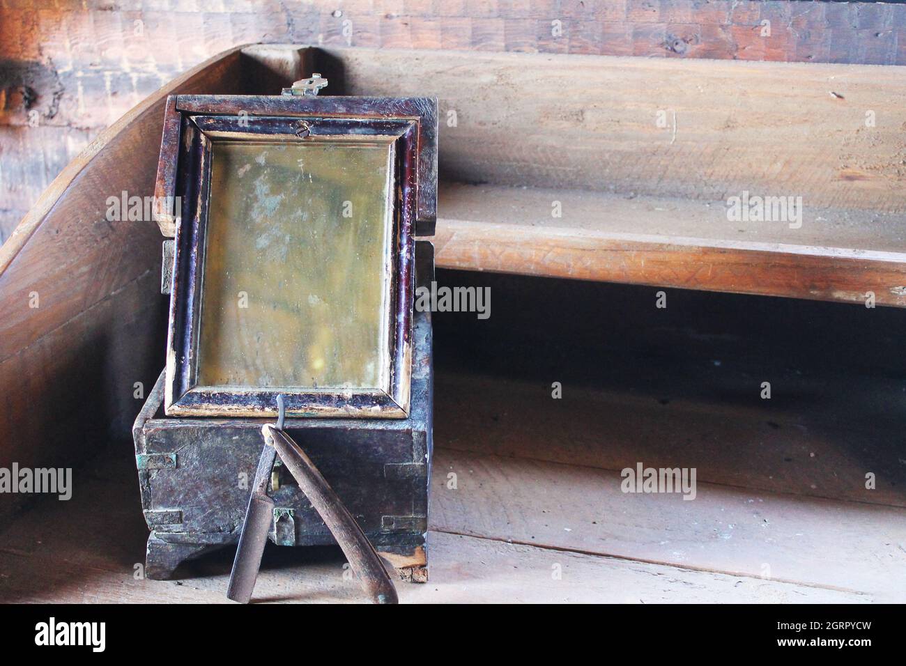Gros plan d'un rasoir ancien et d'un miroir sur un bureau rustique en bois. Banque D'Images