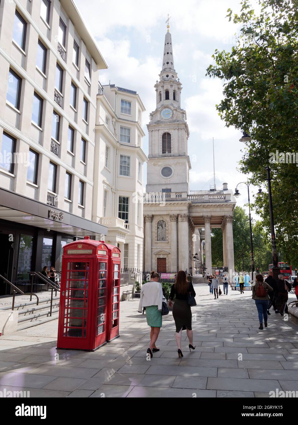 Londres, Grand Londres, Angleterre, septembre 21 2021: Femme passant devant les boîtes téléphoniques avec l'église St Martin dans les champs derrière Trafalgar Square. Banque D'Images