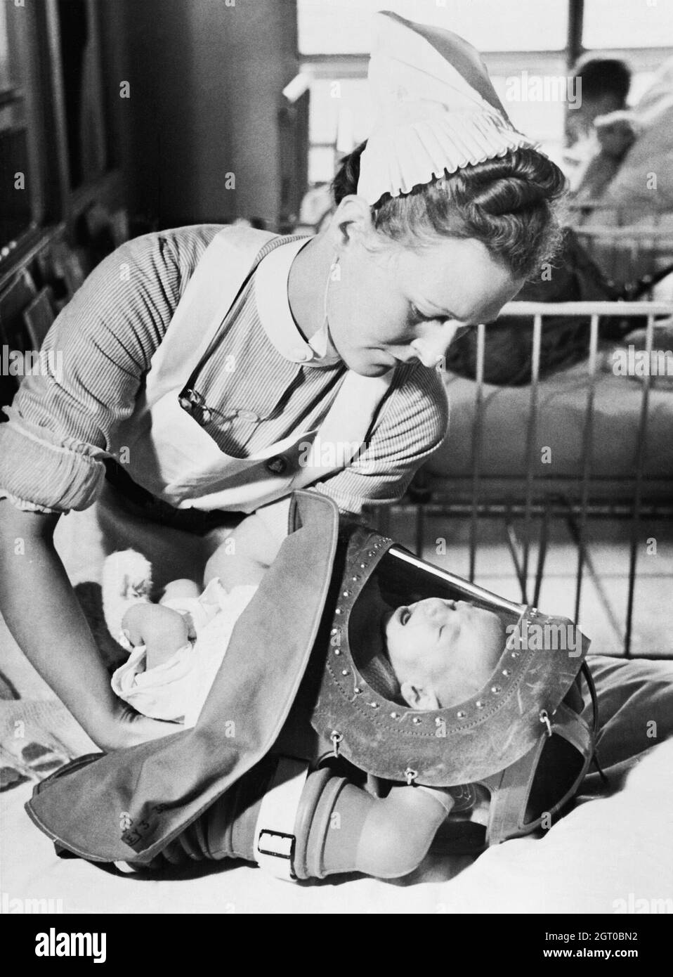 Une infirmière place un bébé qui pleure dans son respirateur de gaz lors d'un exercice dans un hôpital de Londres en 1940. Banque D'Images