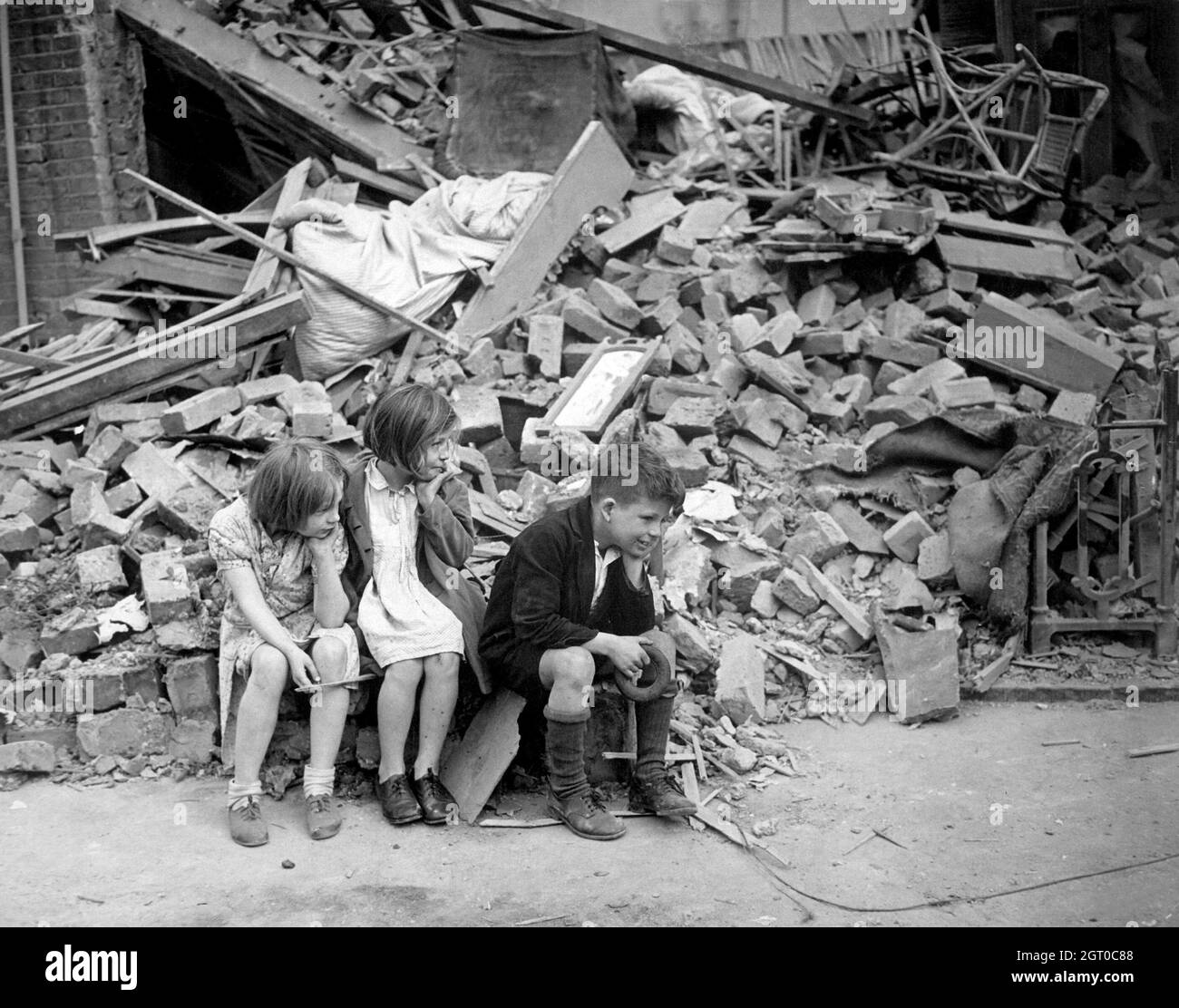 Les enfants choqués se sont assis dans les ruines de leur maison pendant le Blitz en septembre 1940. Banque D'Images
