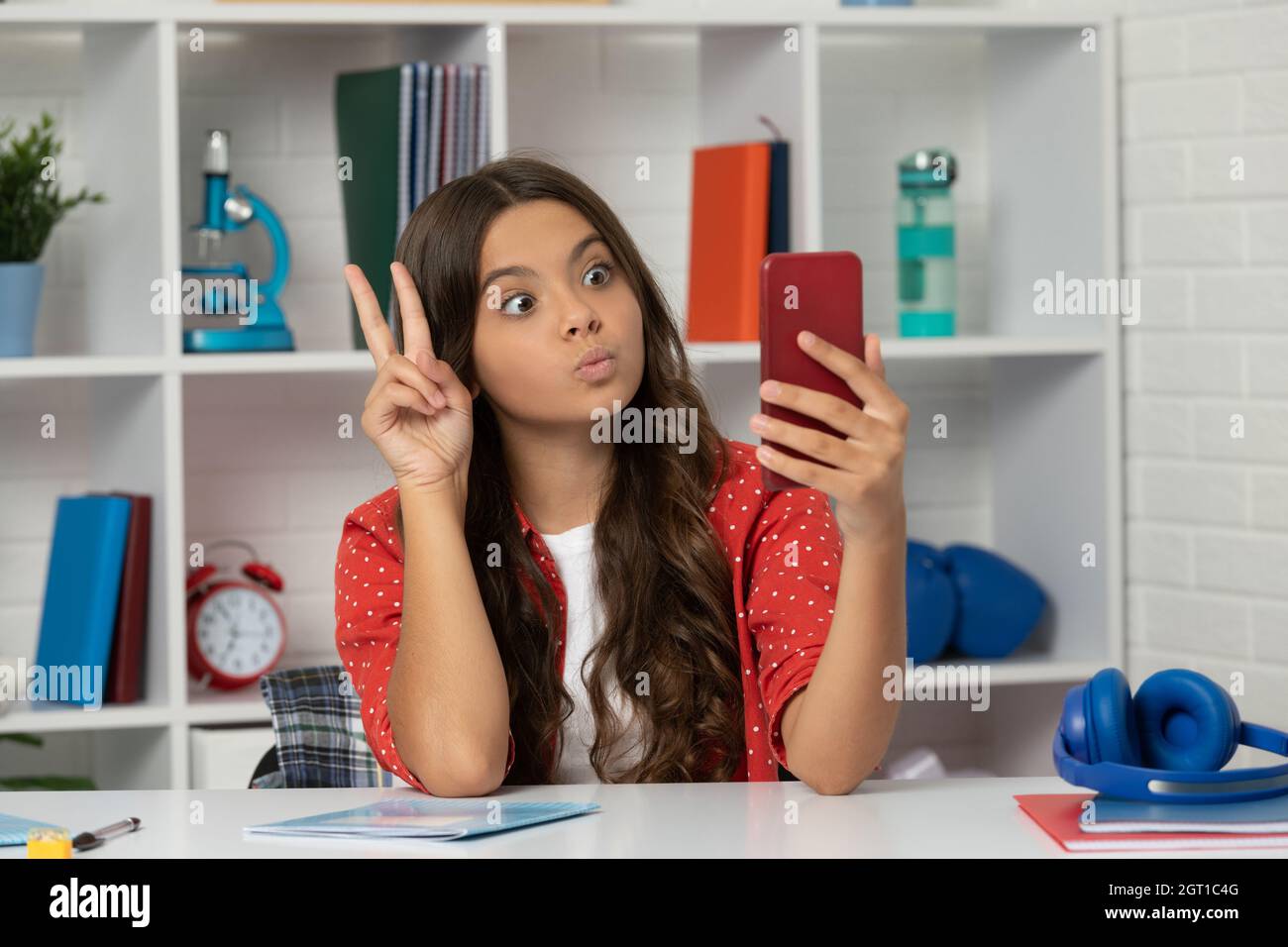 vlogger avec téléphone portable montrer la paix geste. heureux teen fille blogger utiliser smartphone. Banque D'Images