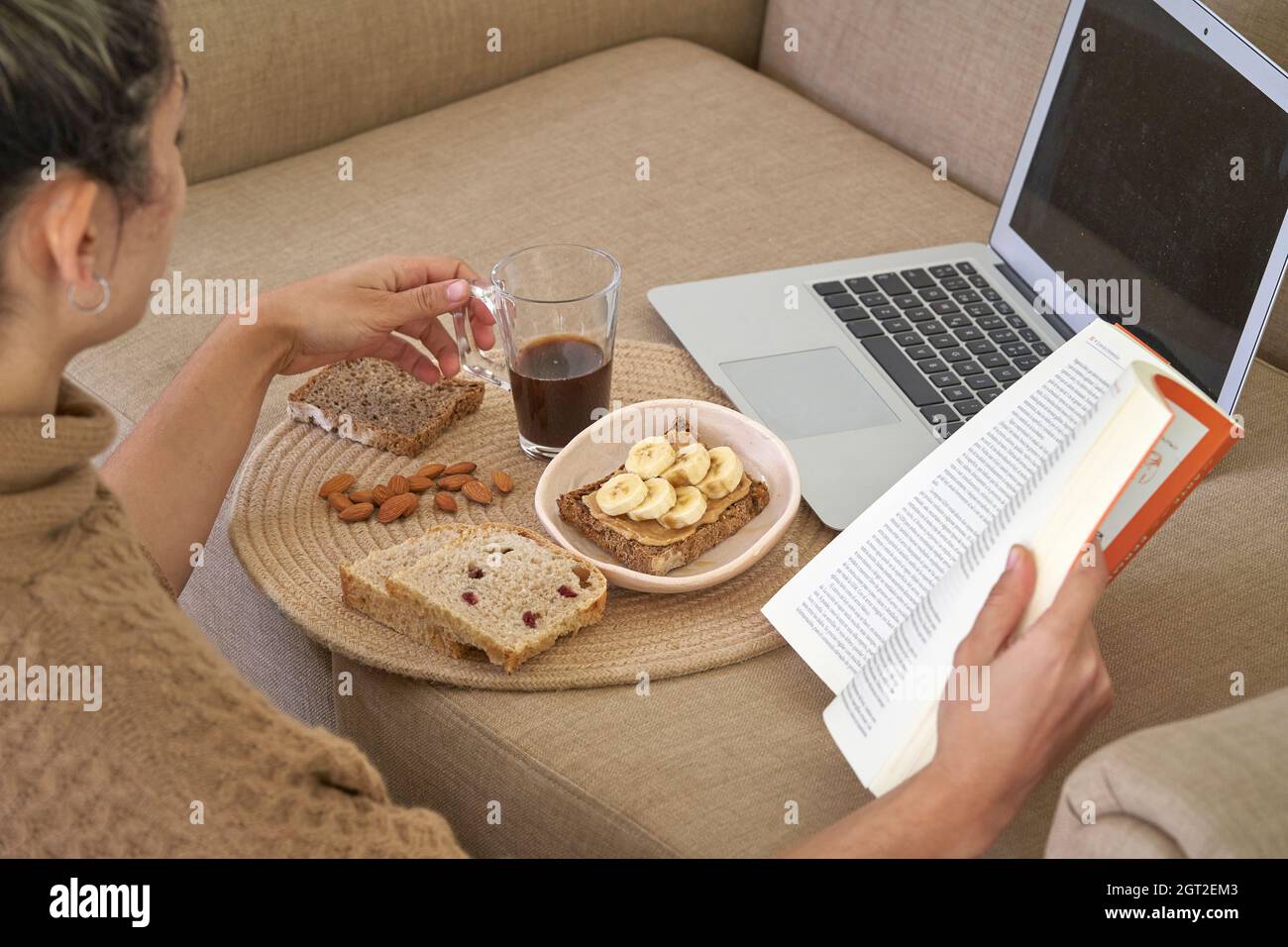 Une femme tient la main cuillère sur un bol de petit déjeuner sain concept appréciez le repas du matin de détox sur le fond de table de travail avec le lait d'ordinateur portable, la femme mange du grano naturel Banque D'Images