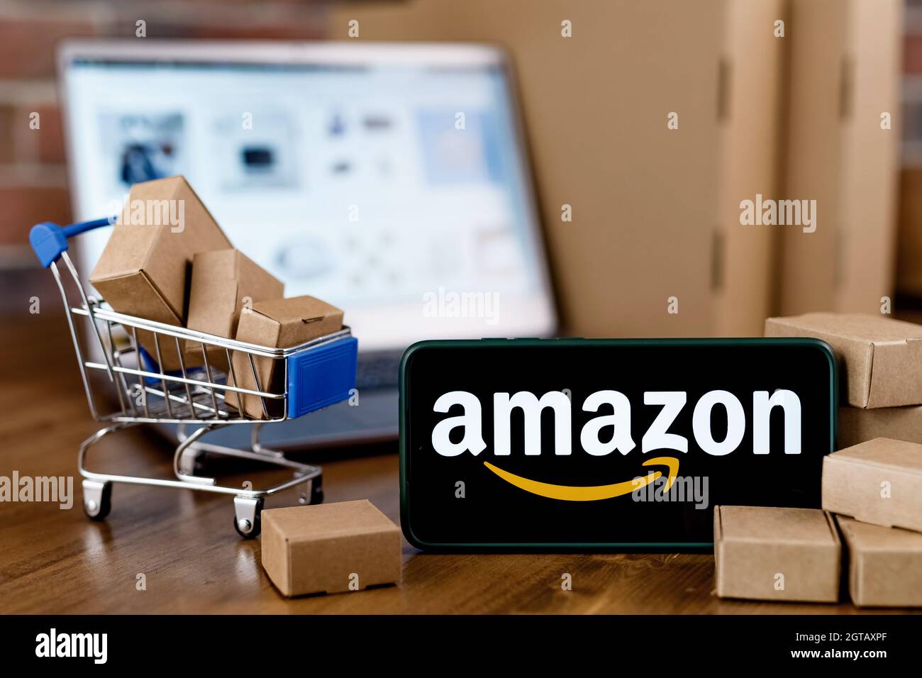 Smartphone avec logo Amazon à l'écran, panier et ordinateur portable. Banque D'Images