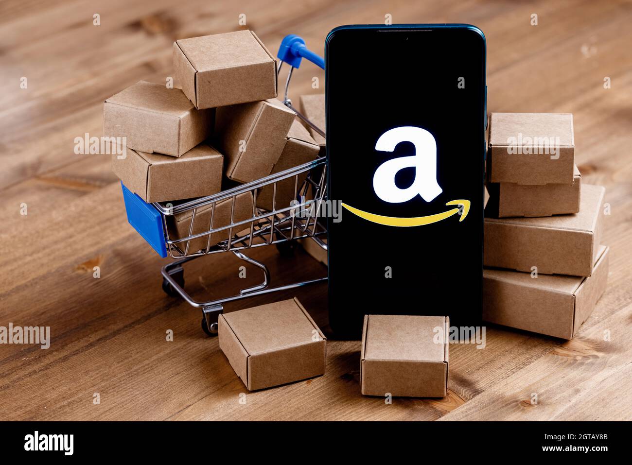 Smartphone avec logo Amazon à l'écran, panier et colis. Banque D'Images