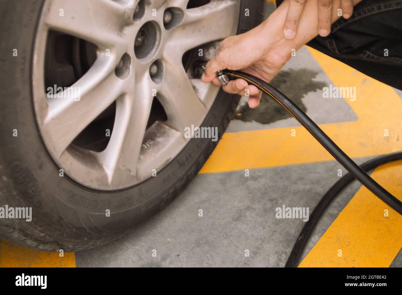 Homme travaillant main avec la machine du système de remplissage de pneus d'azote dans le pneu de voiture Banque D'Images