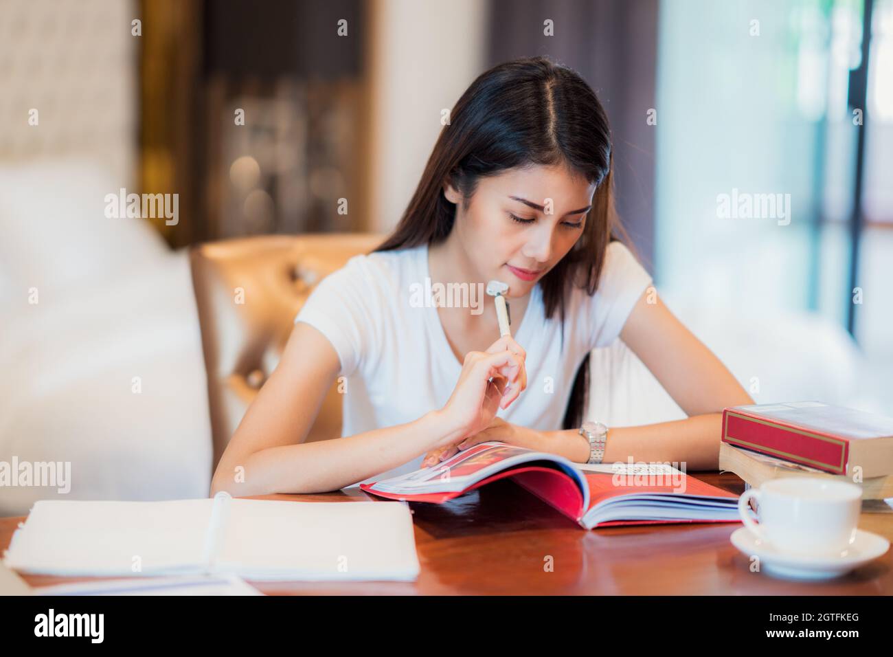 Femme lisant le livre sur la table à la maison Banque D'Images