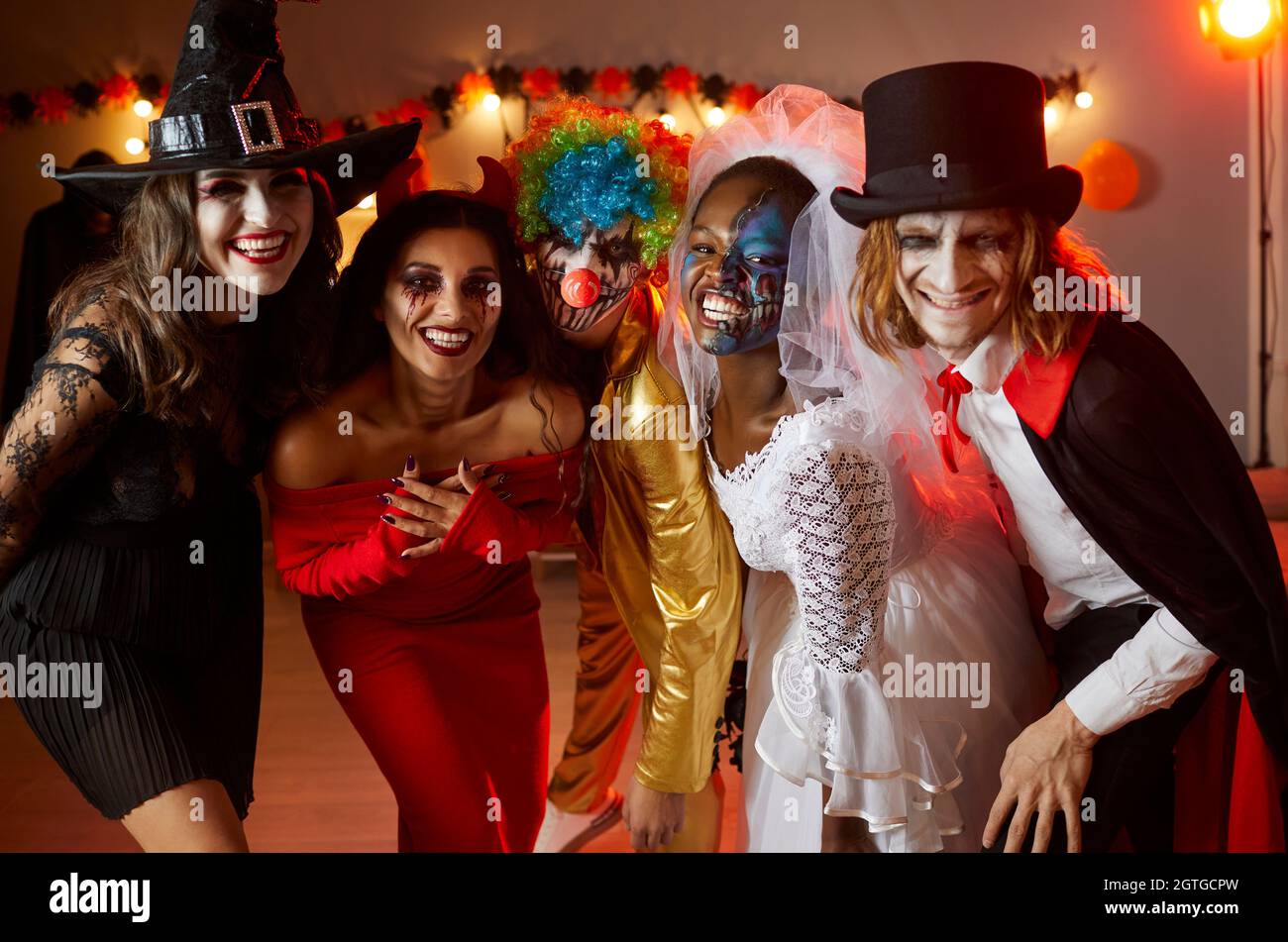 Groupe d'amis heureux vêtus de costumes effrayants d'Halloween debout ensemble et souriant Banque D'Images