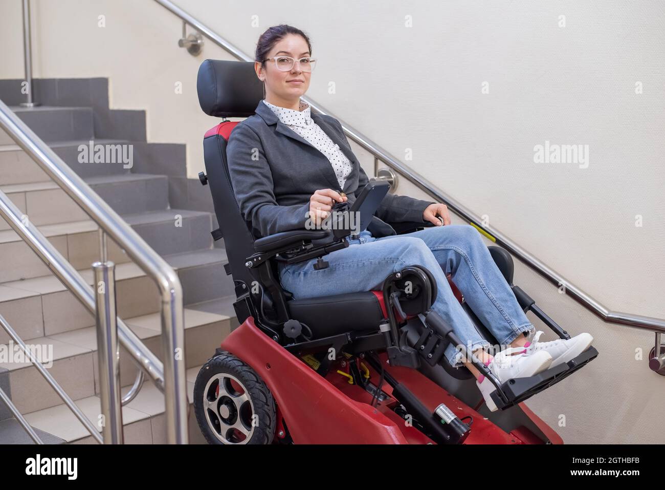 Une femme caucasienne en fauteuil roulant électrique caterpillar monte les  escaliers Photo Stock - Alamy