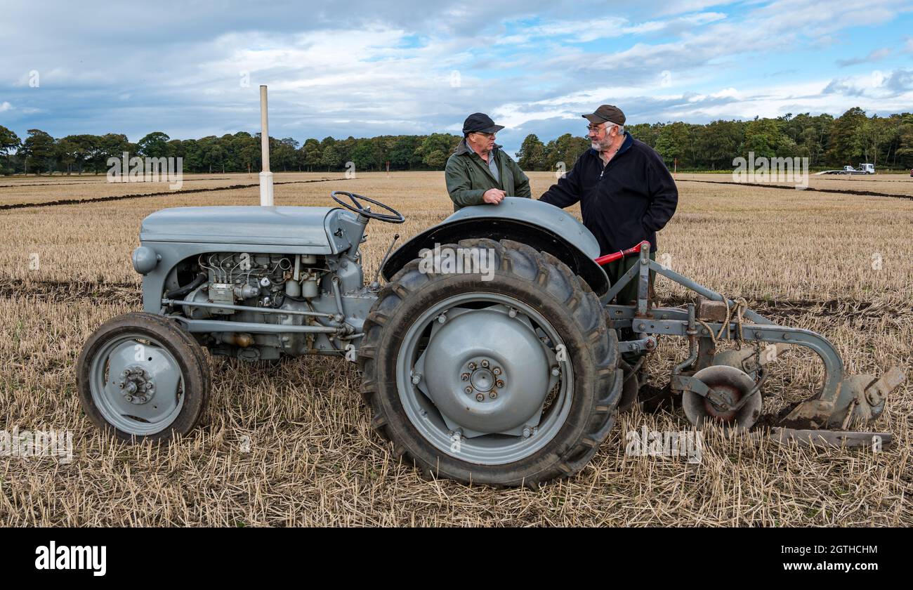 Luffness mains Farm, East Lothian, Écosse, Royaume-Uni, 2 octobre 2021.Match de labour caritatif : les agriculteurs participent à l'événement pour recueillir des fonds pour les championnats écossais de labour qui ont été durement touchés par la pandémie.Les tracteurs sont des modèles horticoles classiques, classiques, classiques et vintage hydrauliques, non hydrauliques et réversibles.Les juges décerne des points pour la rectitude, les ouvertures et les sorties et une variété d'autres caractéristiques des lignes labourées.Photo : deux hommes avec un tracteur hydraulique d'époque Banque D'Images