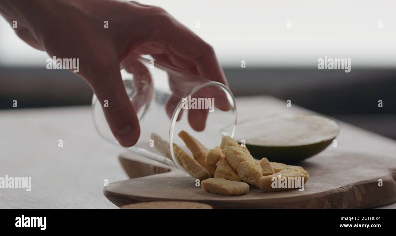 homme verser la mangue séchée sur un pot de verre, sur une planche de bois d'olive, photo large Banque D'Images