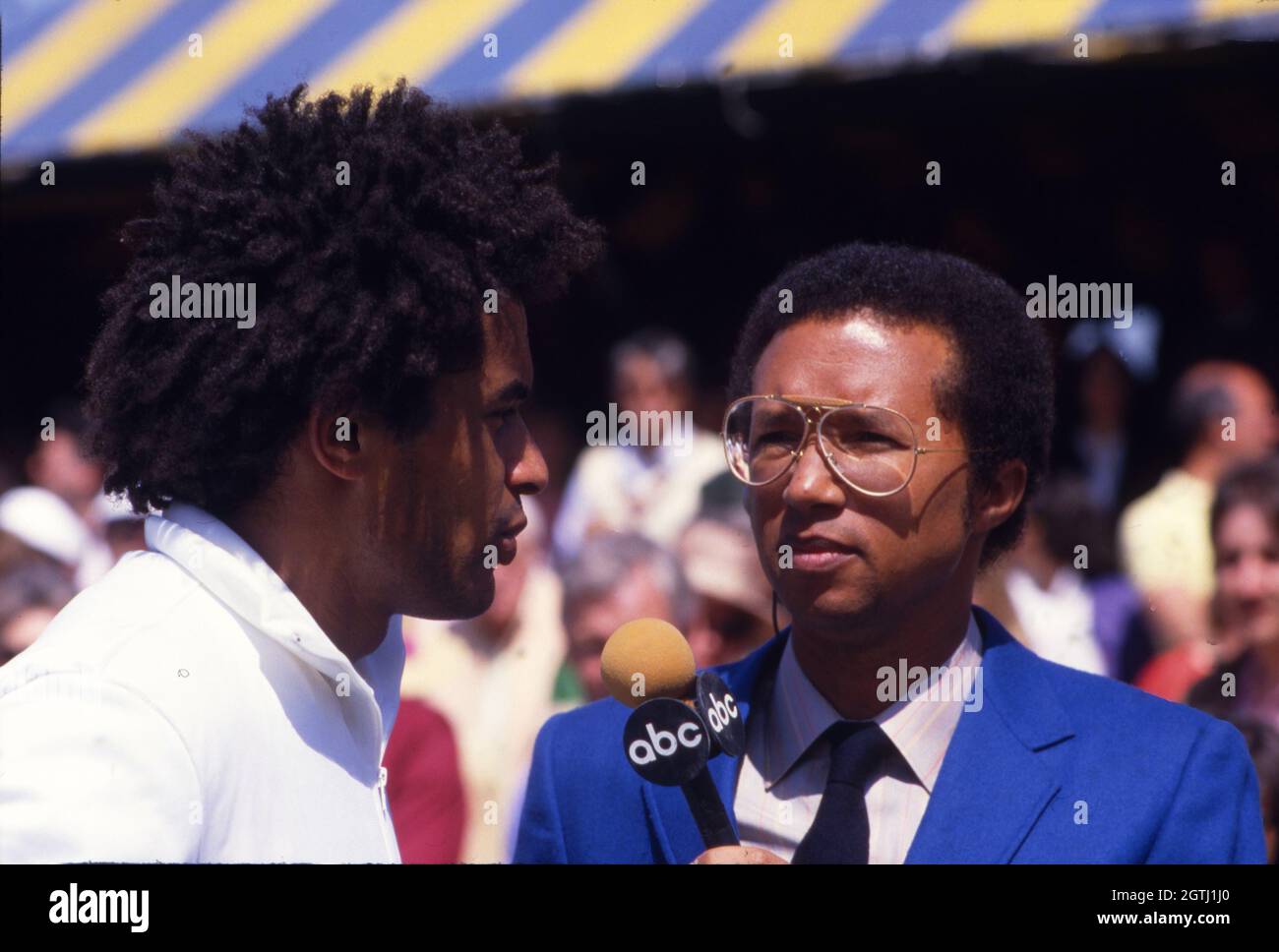 Arthur Ashe, alors en tant que correspondant d'ABC Sports, interviewer Yannick Noah lors d'un tournoi de tennis de championnat du monde à Forest Hills, New York en 1986 Banque D'Images