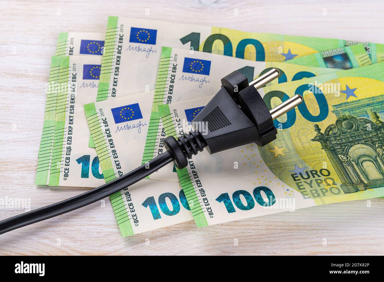 Fiche électrique noire sur cent billets en euros. Augmentation du coût de l'électricité pour les clients résidentiels et les utilisateurs professionnels. Paiement de l'électricité Banque D'Images