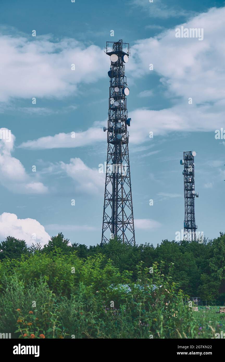 Deux mâts de télécommunications antennes TV technologie sans fil contre ciel bleu sur les bords verts, style couleur froide Banque D'Images