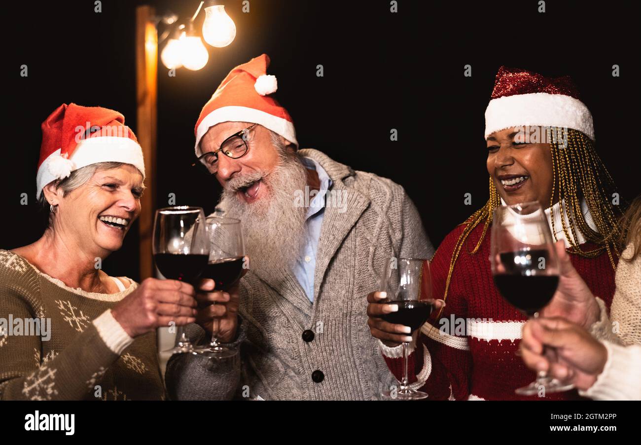 De joyeux amis senior célébrant les vacances de Noël tout en dégustant du rouge verres à vin sur le patio de la maison fête Banque D'Images