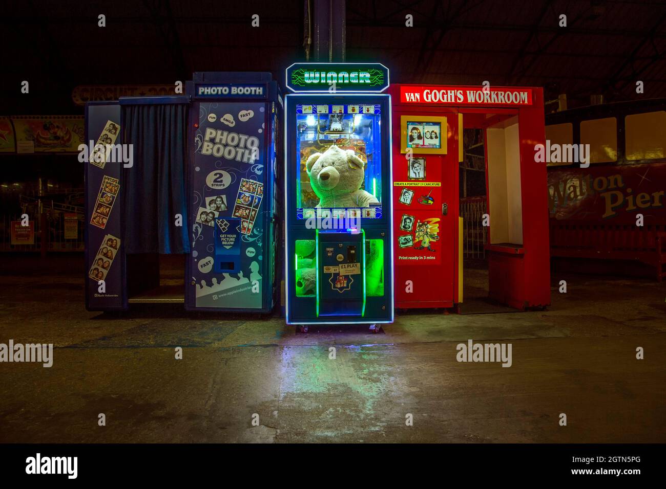 Une machine à griffes avec un signe lumineux lisant Winner tient un grand ours en peluche. L'ours a l'air oublié car il n'y a pas de personnes autour. Banque D'Images