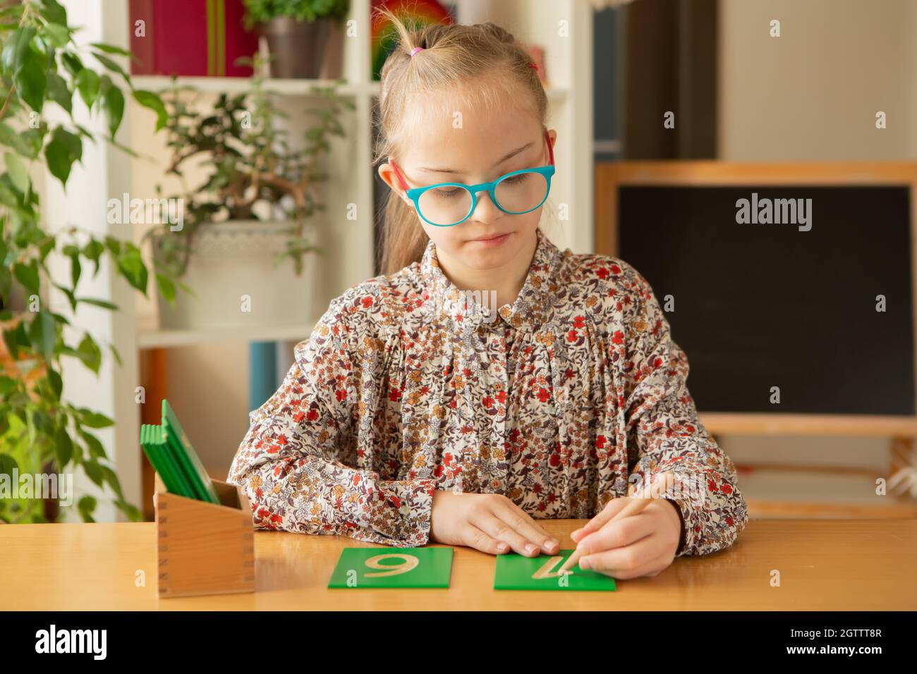 Une belle fille avec le syndrome de Down est engagée dans la classe, étudiant les nombres Banque D'Images