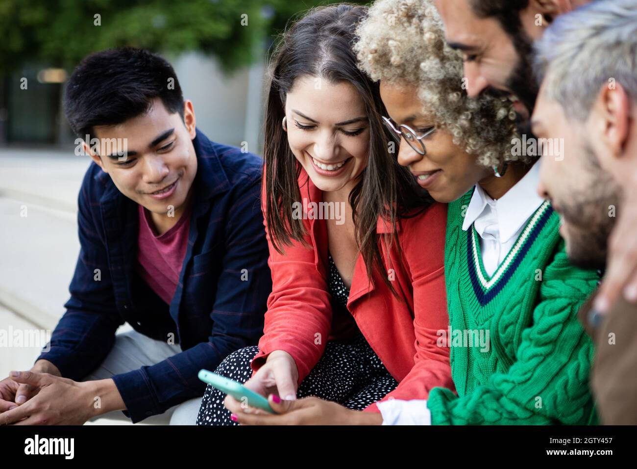 Groupe de jeunes qui s'amusent tout en regardant du contenu vidéo sur leur téléphone mobile Banque D'Images