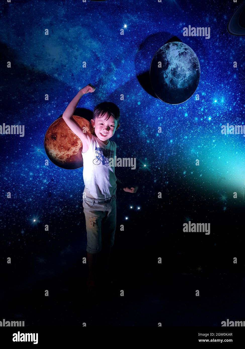 Portrait de garçon souriant Flexing muscles tout en se tenant contre le mur de modèle d'espace Banque D'Images