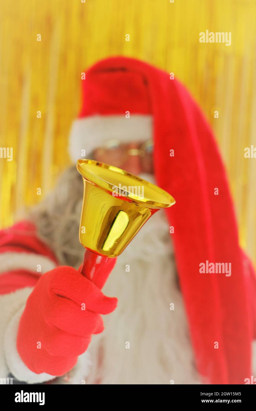 Saison de Noël. Père Noël avec cloche dorée sur fond doré. Joyeux Noël. Vacances de Noël Banque D'Images