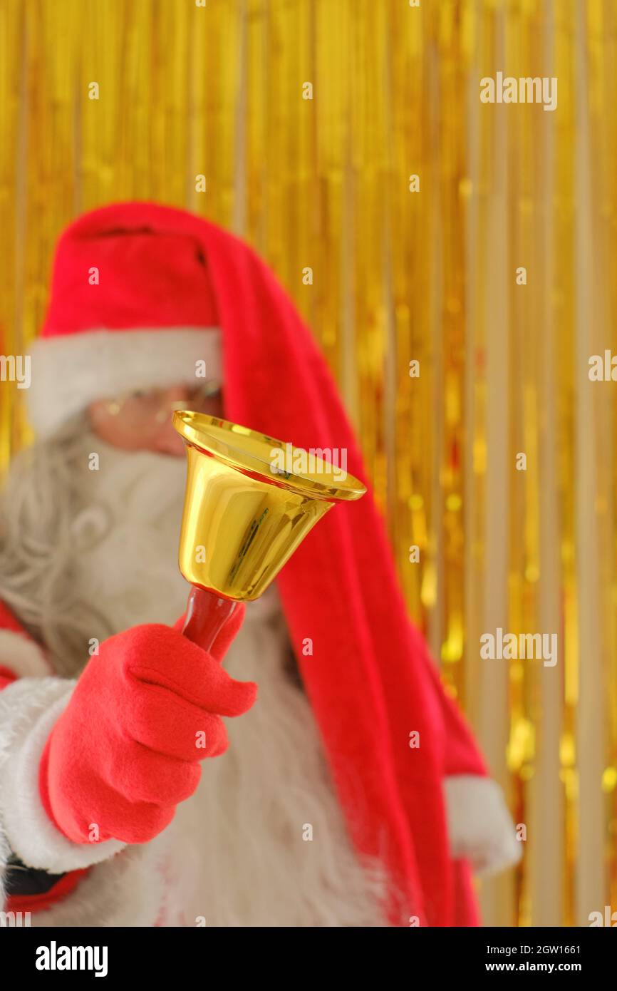 Saison de Noël. Père Noël avec cloche dorée sur fond doré flou. Joyeux Noël. Vacances de Noël Banque D'Images