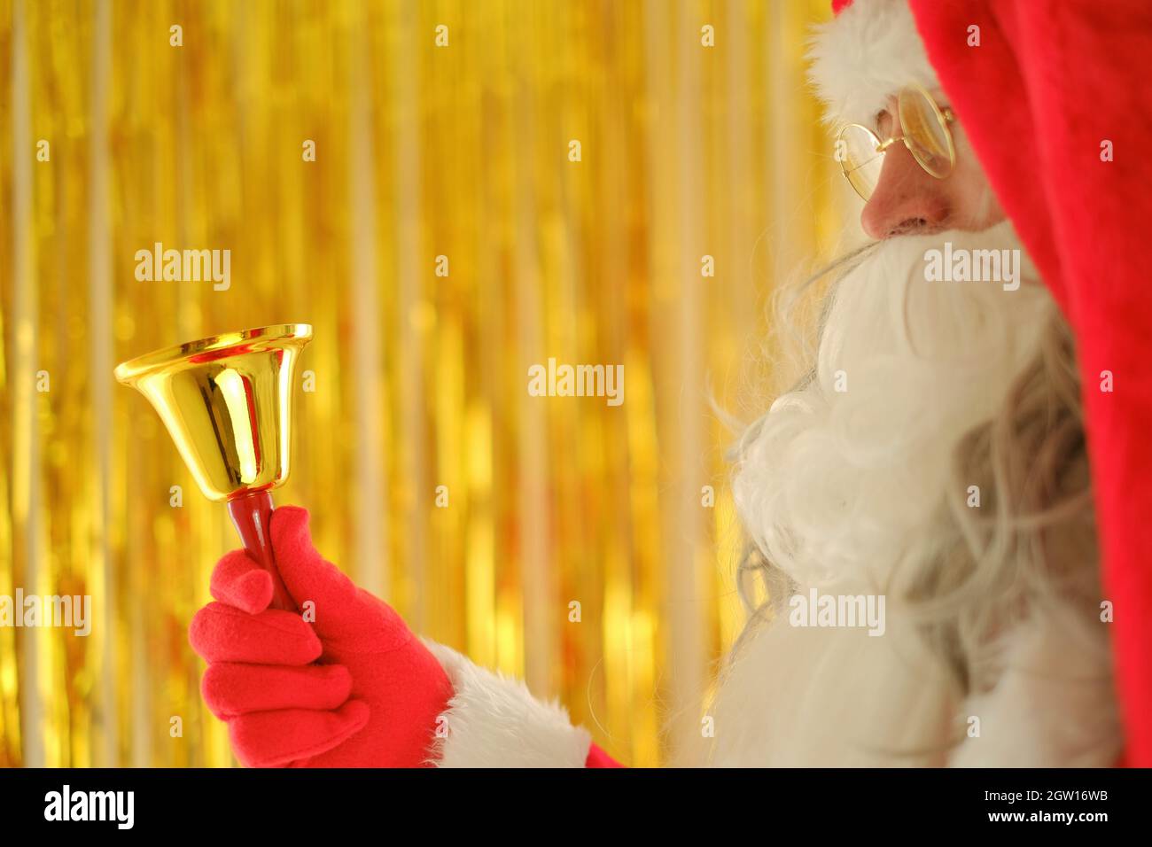 Saison de Noël. Père Noël avec cloche dorée sur fond doré flou. Joyeux Noël. Historique des ventes des fêtes de Noël Banque D'Images