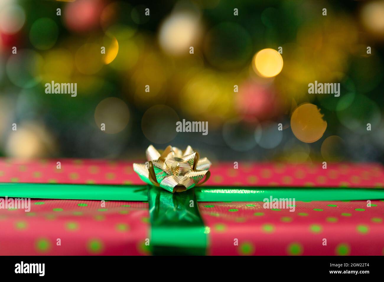 Cadeau de Noël en papier rouge avec ruban doré sur l'arbre de noël Banque D'Images