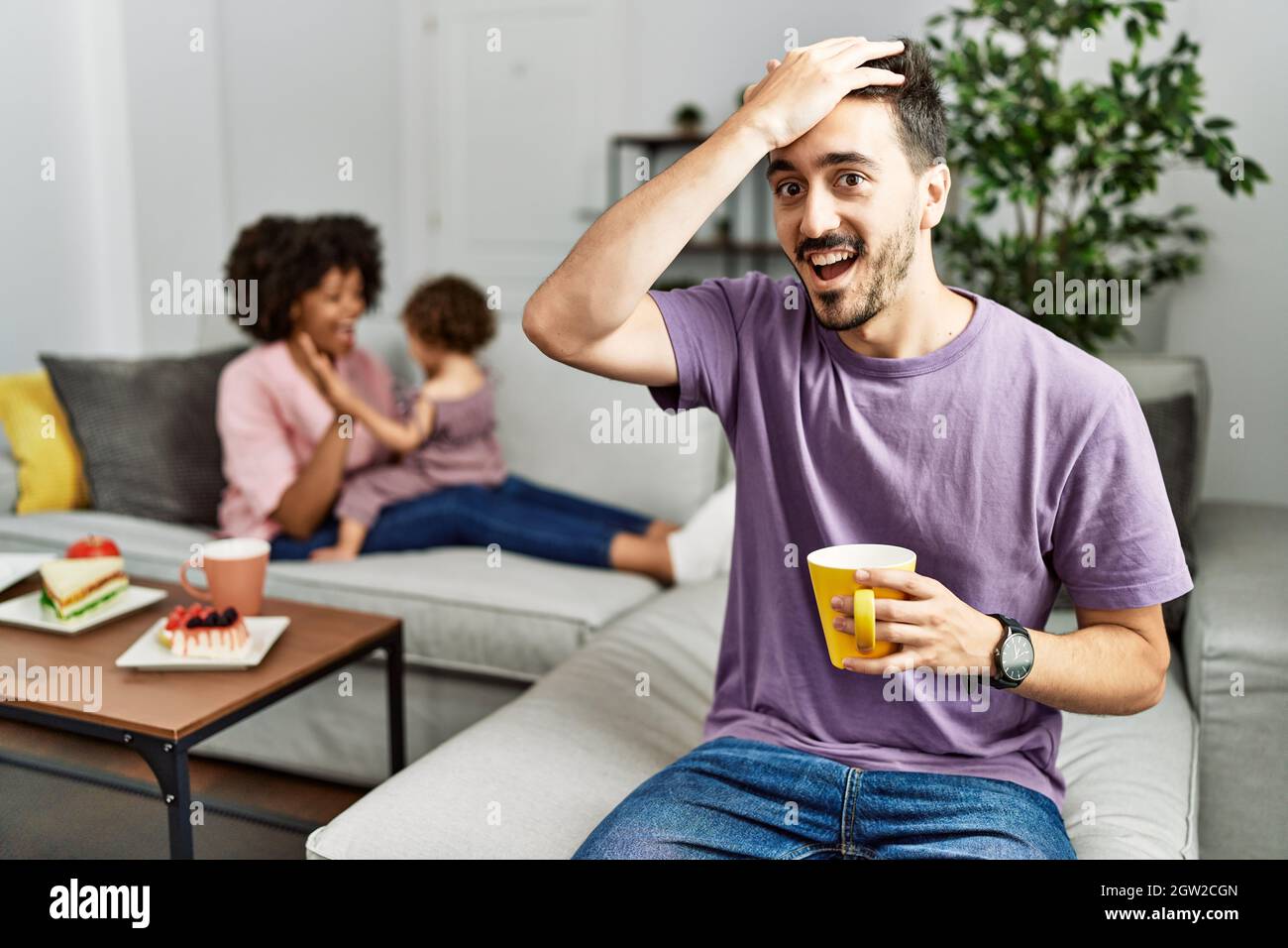 Père hispanique de famille interraciale boire une tasse de café surpris par la main sur la tête pour l'erreur, souvenez-vous de l'erreur. oublié, mauvais concept de mémoire. Banque D'Images Père hispanique de famille interraciale boire une tasse de café surpris par la main sur la tête pour l'erreur, souvenez-vous de l'erreur. oublié, mauvais concept de mémoire. Banque D'Images