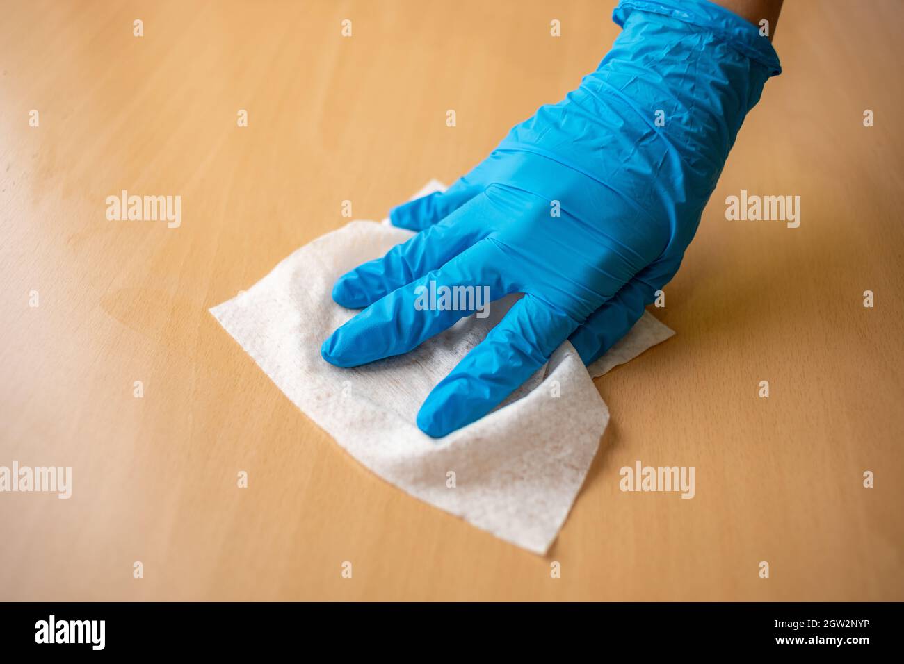Main de femme en gants bleus aseptisation nettoyage à la maison Bureau  surface de la table en bois avec des lingettes humides Photo Stock - Alamy