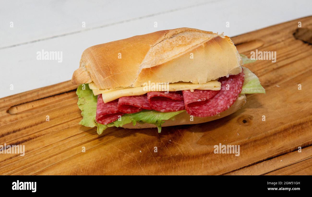 Vue rapprochée d'un salami maison, fromage et sandwich à la laitue, sur une assiette en bois Banque D'Images