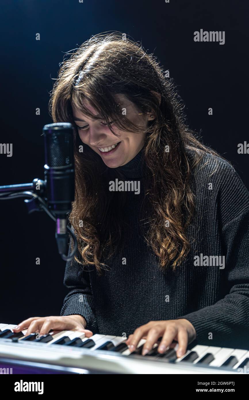 Fille gaie dans le processus d'enregistrement de contenu musical dans le studio, l'enregistrement de la voix dans un microphone professionnel, le concept d'apprentissage du piano Banque D'Images