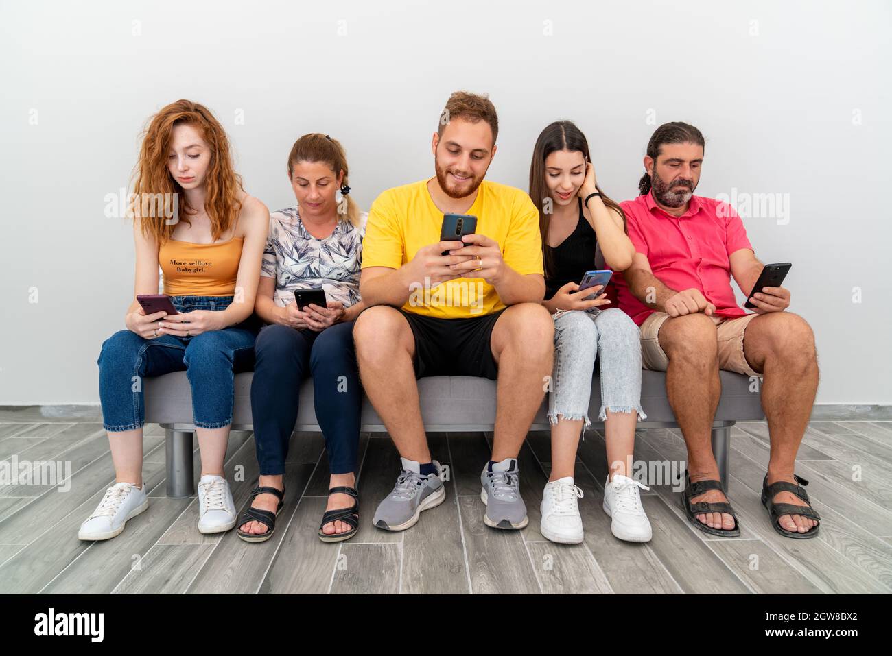 Groupe d'amis assis sur un canapé et regardant leur téléphone portable. Concept de dépendance technologique. Photo de haute qualité Banque D'Images