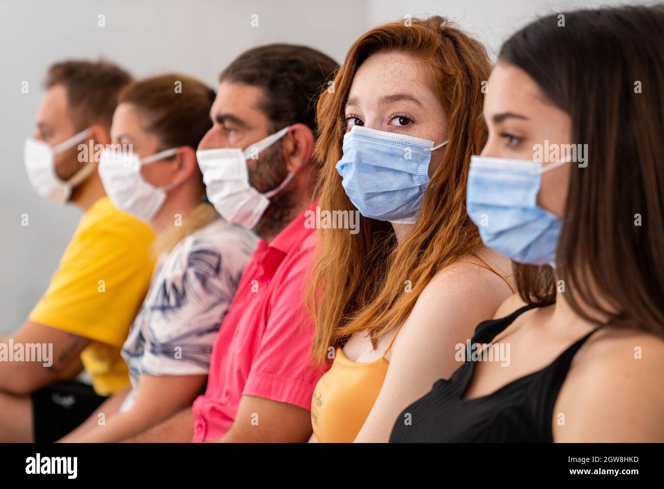 Groupe de personnes est assis et attend dans un hall avec masque facial protecteur à distance sociale. Pandémie et concept de soins de santé. Photo de haute qualité Banque D'Images