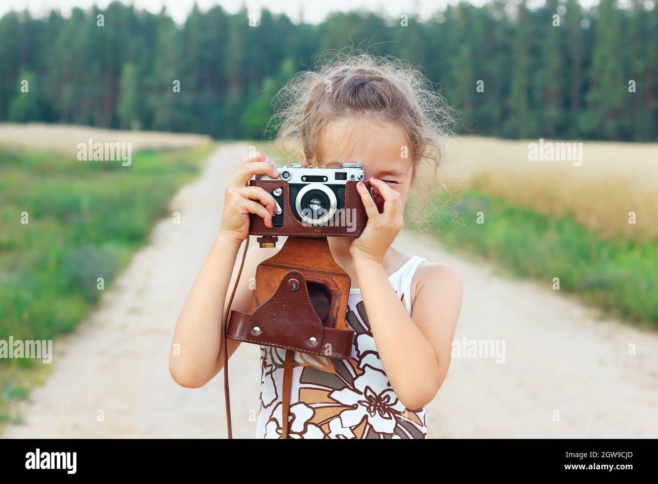 Bonne belle petite fille dans la tenue retro est de prendre des photos avec l ancien appareil photo de film Photo Stock Alamy