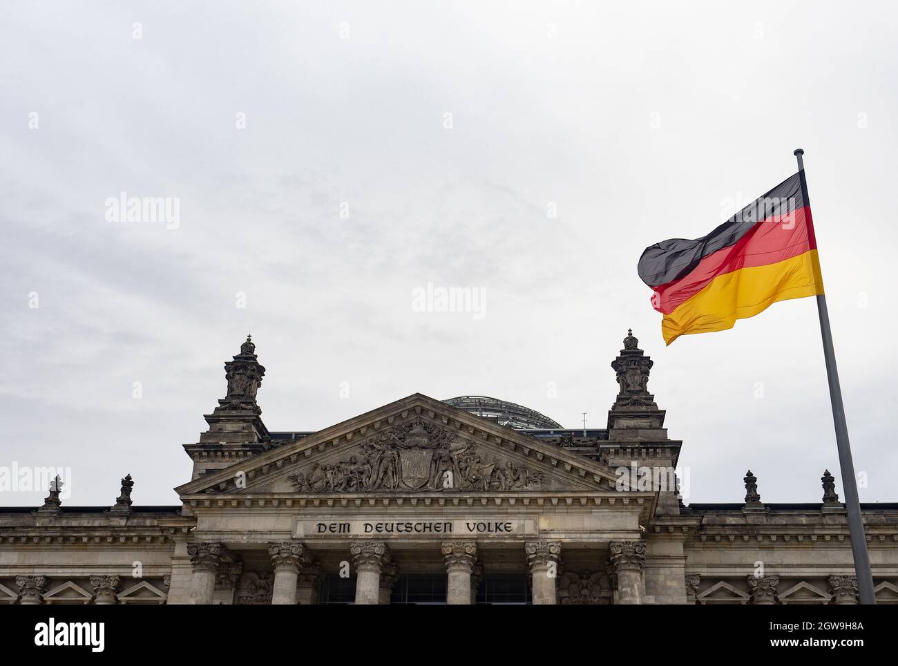 Berlin, Allemagne. 03ème octobre 2021. Un drapeau allemand vole devant le Reichstag le jour de l'unité allemande. La loi allemande sur la Journée de l'unité est entrée en vigueur le 4 août 1953. À l'avenir, le 17 juin devait servir de jour commémoratif national officiel pour commémorer le soulèvement de 1953 dans la RDA. Depuis la réunification allemande en 1990, la « Journée de l'unité allemande » a été célébrée le 3 octobre. Credit: Paul Zinken/dpa/Alay Live News Banque D'Images
