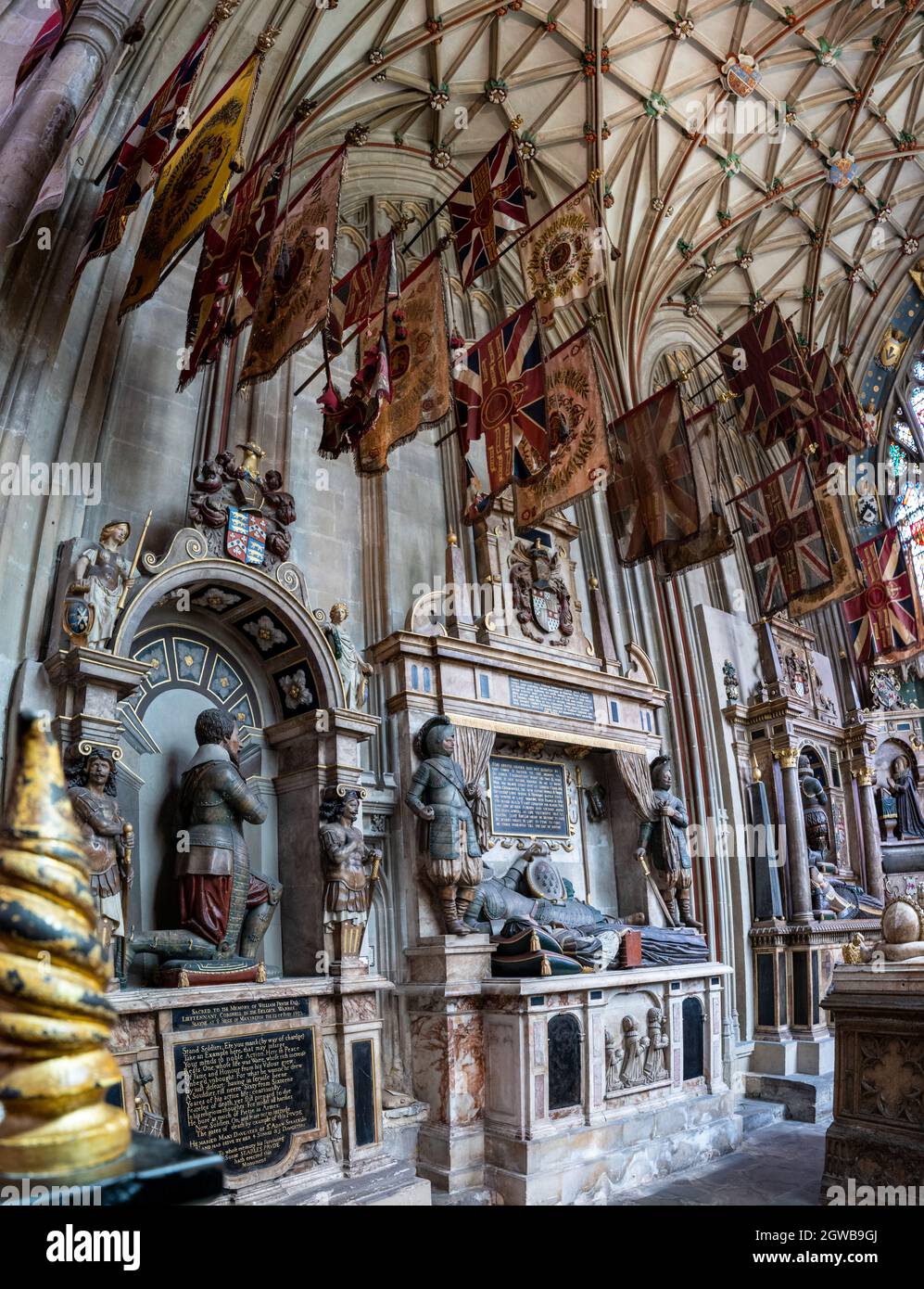 Intérieur gothique orné de tombes en pierre élaborées et bannières héraldiques colorées Banque D'Images
