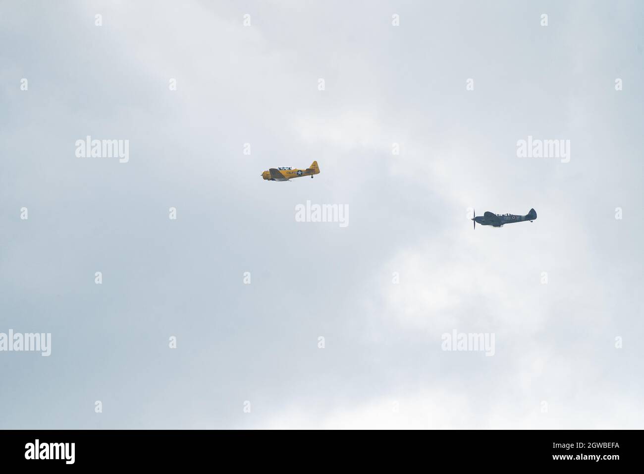 Deux avions de guerre vintage volant en formation contre un ciel nuageux Banque D'Images