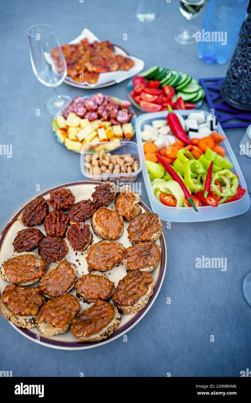 Assortiment de canapés, tapas, légumes, noix, fromage, salami et tartiner sur le pain, boisson sur la table de fête bleue. Banque D'Images