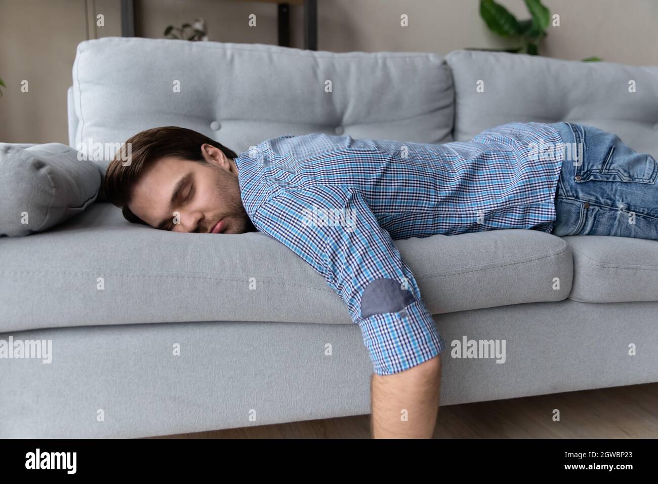 Homme épuisé allongé sur un canapé confortable à la maison, dormant Photo  Stock - Alamy