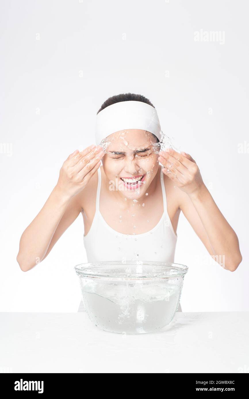 Vue latérale de la femme se lavant le visage sur fond blanc Banque D'Images