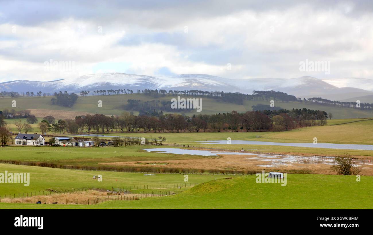 Biggar, Écosse - 3 mars 2020: Vue sur les pâturages en partie inondés vers les collines enneigées de Broughton Heights Banque D'Images