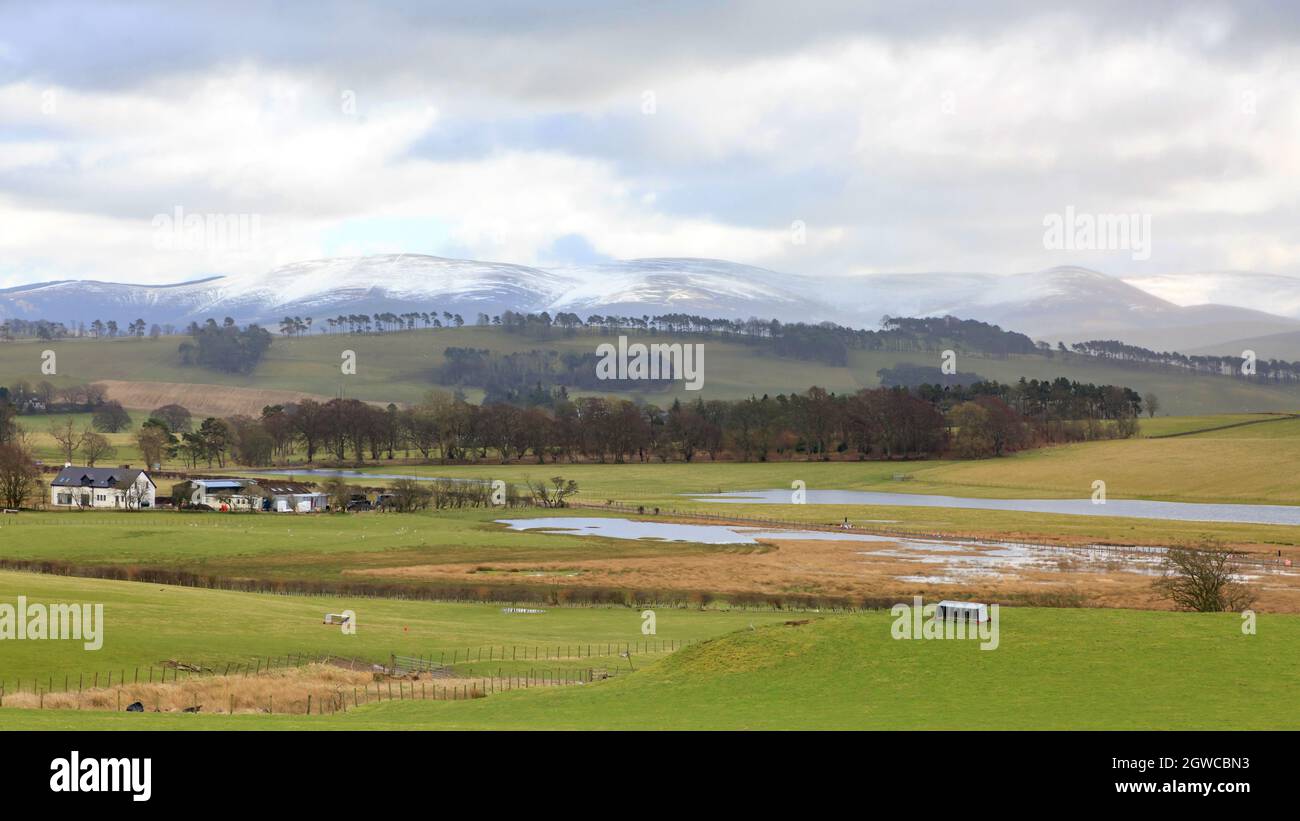 Vue sur les terres agricoles écossaises partiellement inondées vers les collines enneigées Banque D'Images