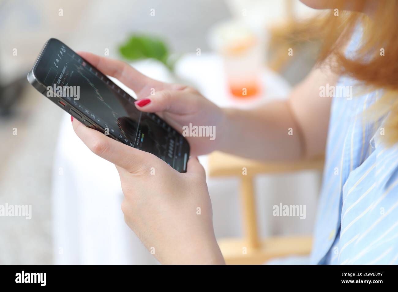Main féminine avec smartphone trading stocks en ligne dans le café concept d'affaires Banque D'Images