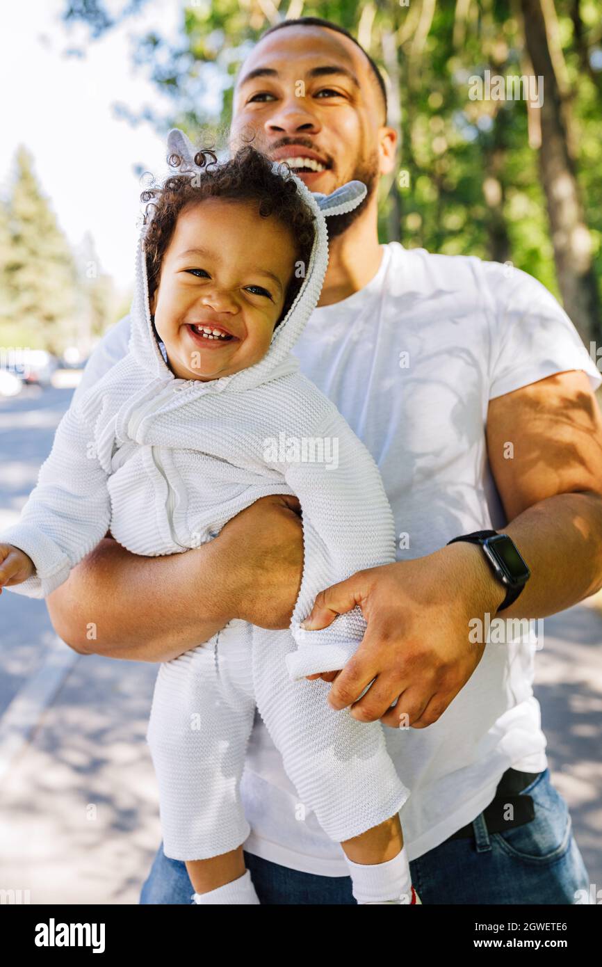 Homme transportant un bébé heureux au parc Banque D'Images