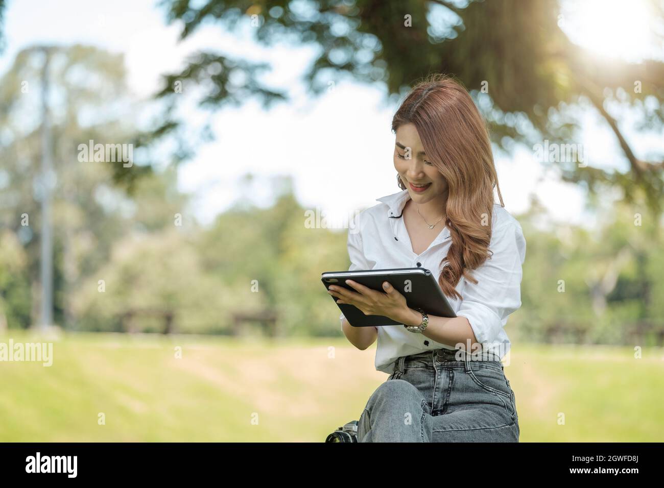 Une jeune fille étudiante travaillant avec une tablette numérique dans un parc vert Banque D'Images