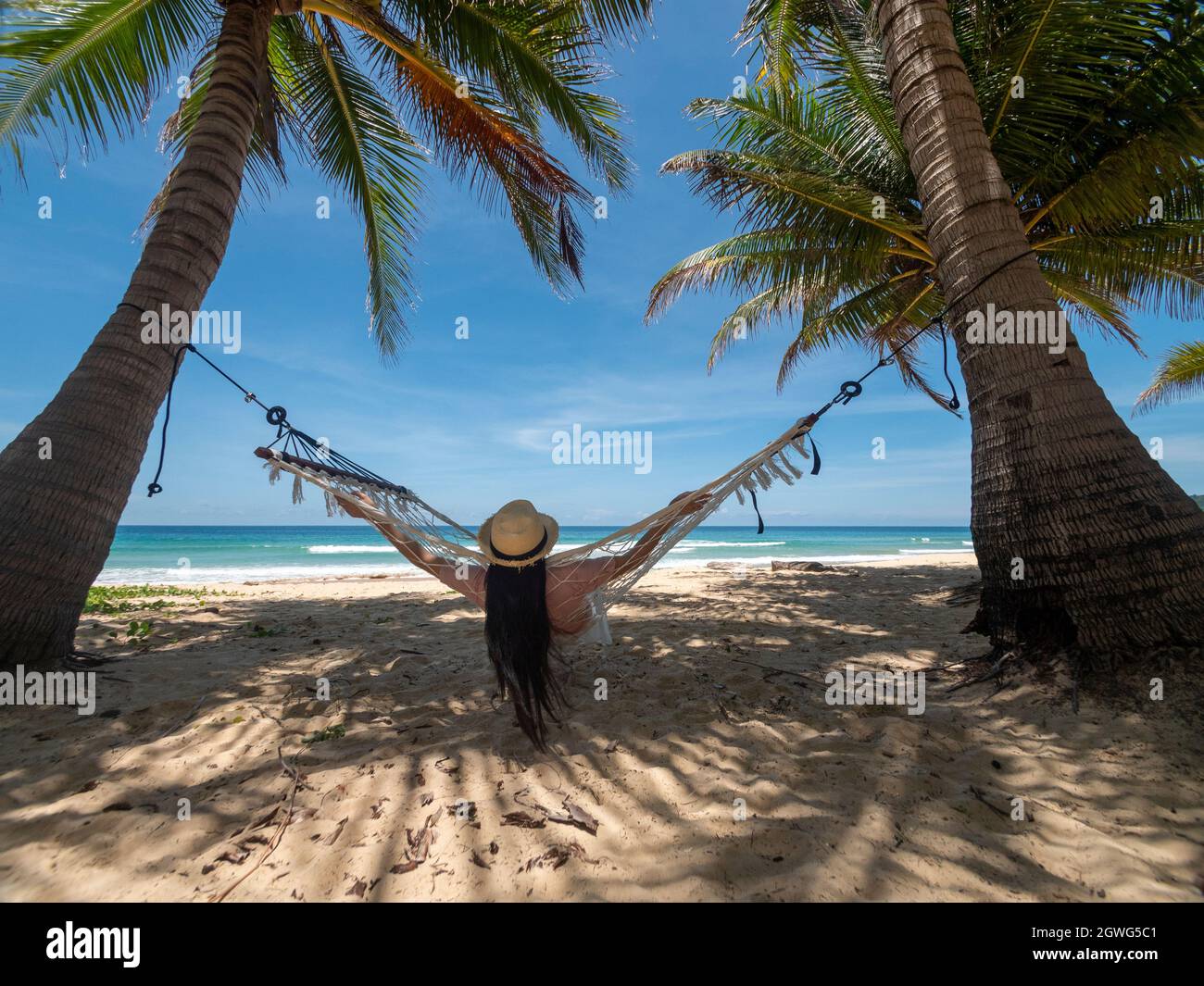 Phuket Thaïlande. Une jeune femme asiatique se détendant sur un hamac près de la plage au coucher du soleil. Jeune femme attrayante balançant sur hamac. Vacances d'été Banque D'Images