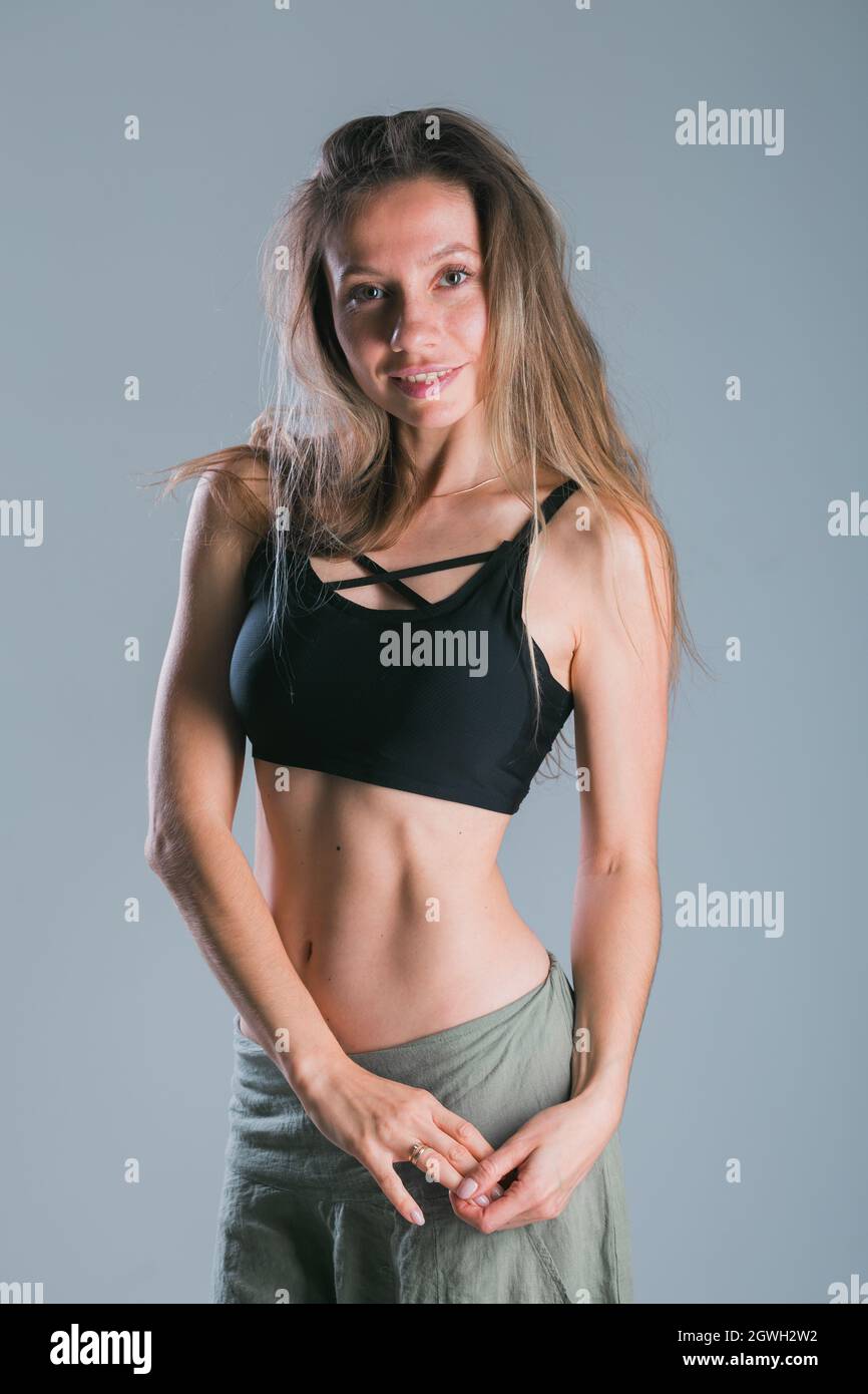 Une jeune fille de forme physique avec un corps sportif posé au studio sur fond gris. Modèle sportif souriant. Perte de poids. Un mode de vie sain. Sportif en bonne santé Banque D'Images